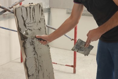 Worker spreading adhesive mix over tile with spatula, closeup