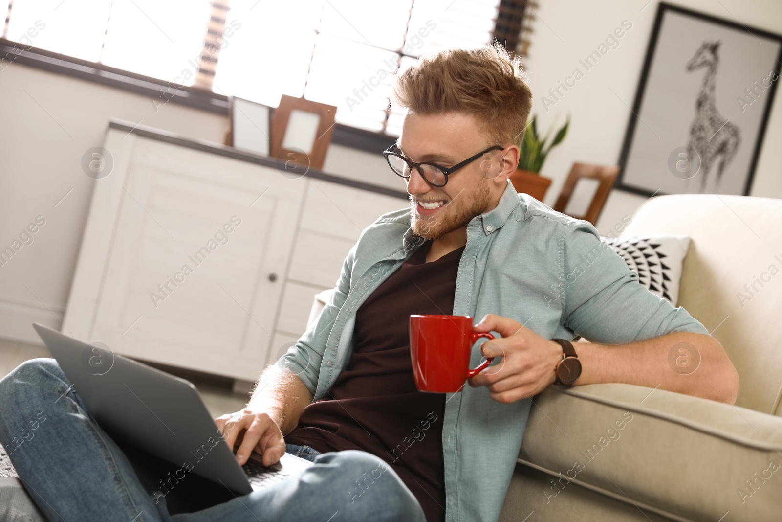 Photo of Young man using laptop in living room