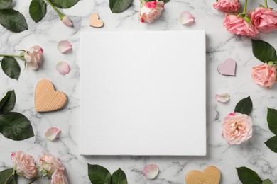 Photo of Flat lay composition with blank canvas and beautiful roses on white marble background. Mockup for design