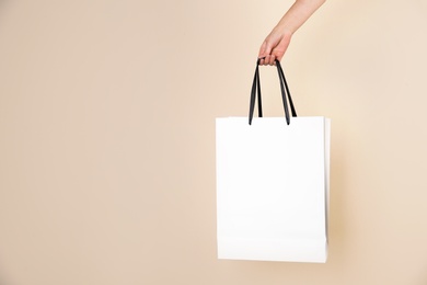 Photo of Woman holding paper shopping bag on color background. Mock up for design