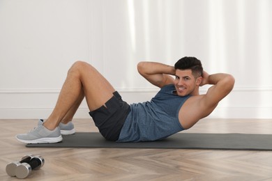 Photo of Handsome man doing abs exercise on yoga mat indoors