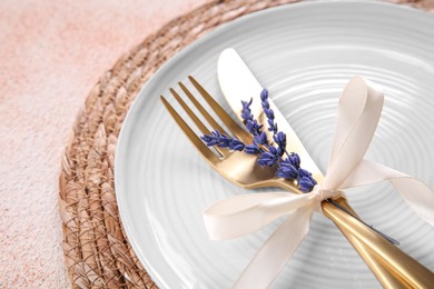 Photo of Cutlery, plate and preserved lavender flowers on color textured table, closeup. Space for text