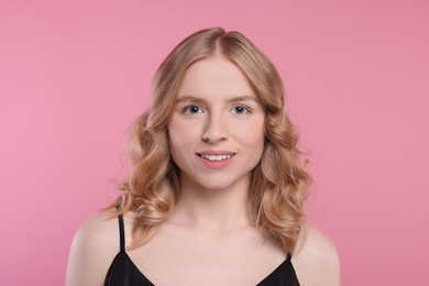 Portrait of beautiful woman with blonde hair on pink background