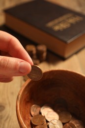 Photo of Donate and give concept. Woman putting coin into bowl at table, closeup
