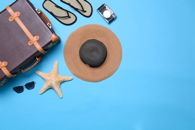 Photo of Vintage suitcase and beach objects on blue background, flat lay. Space for text