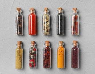 Glass bottles with different spices on gray background