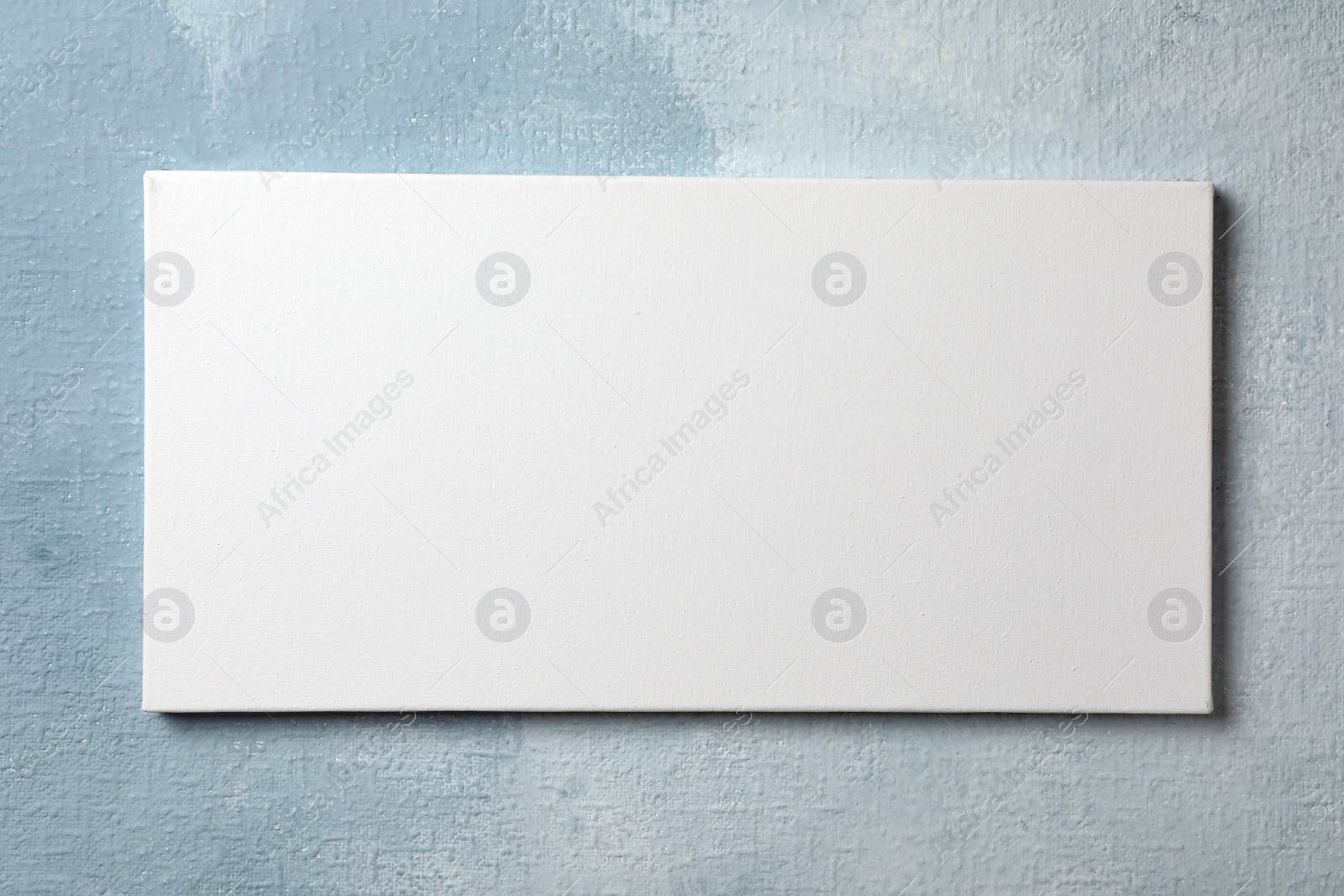 Photo of Blank canvas hanging on light blue wall, space for text