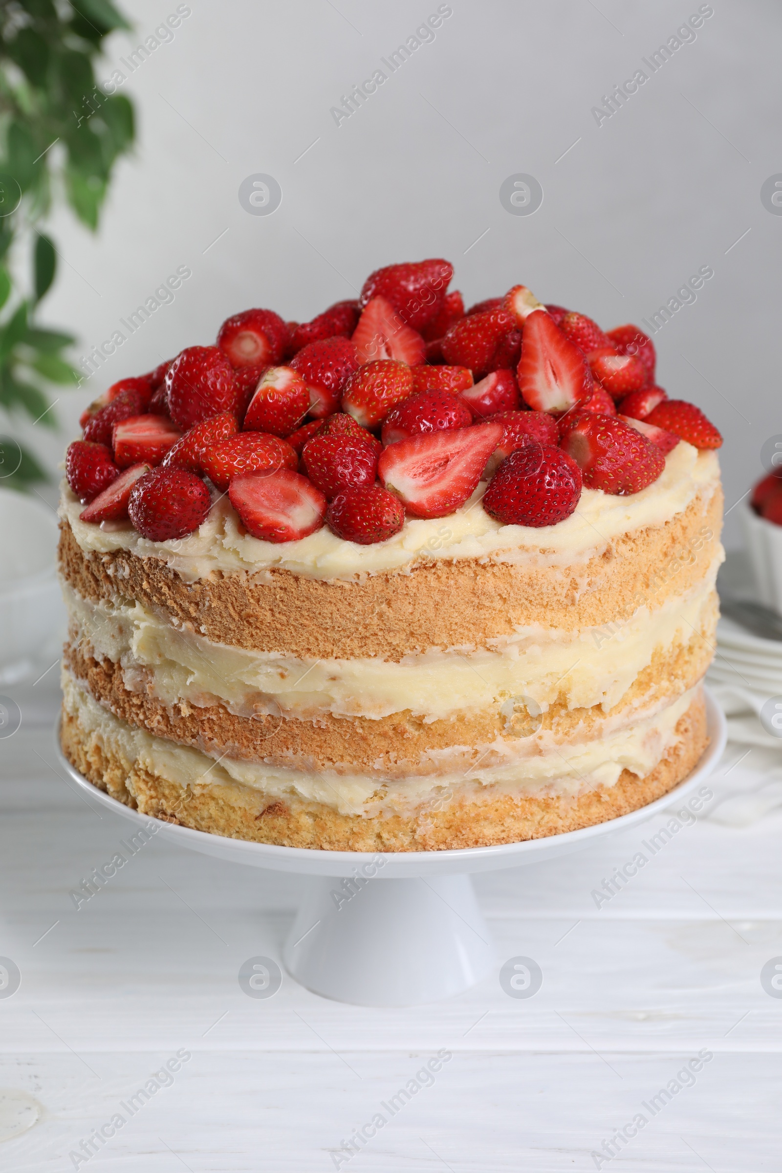 Photo of Tasty cake with fresh strawberries on white wooden table