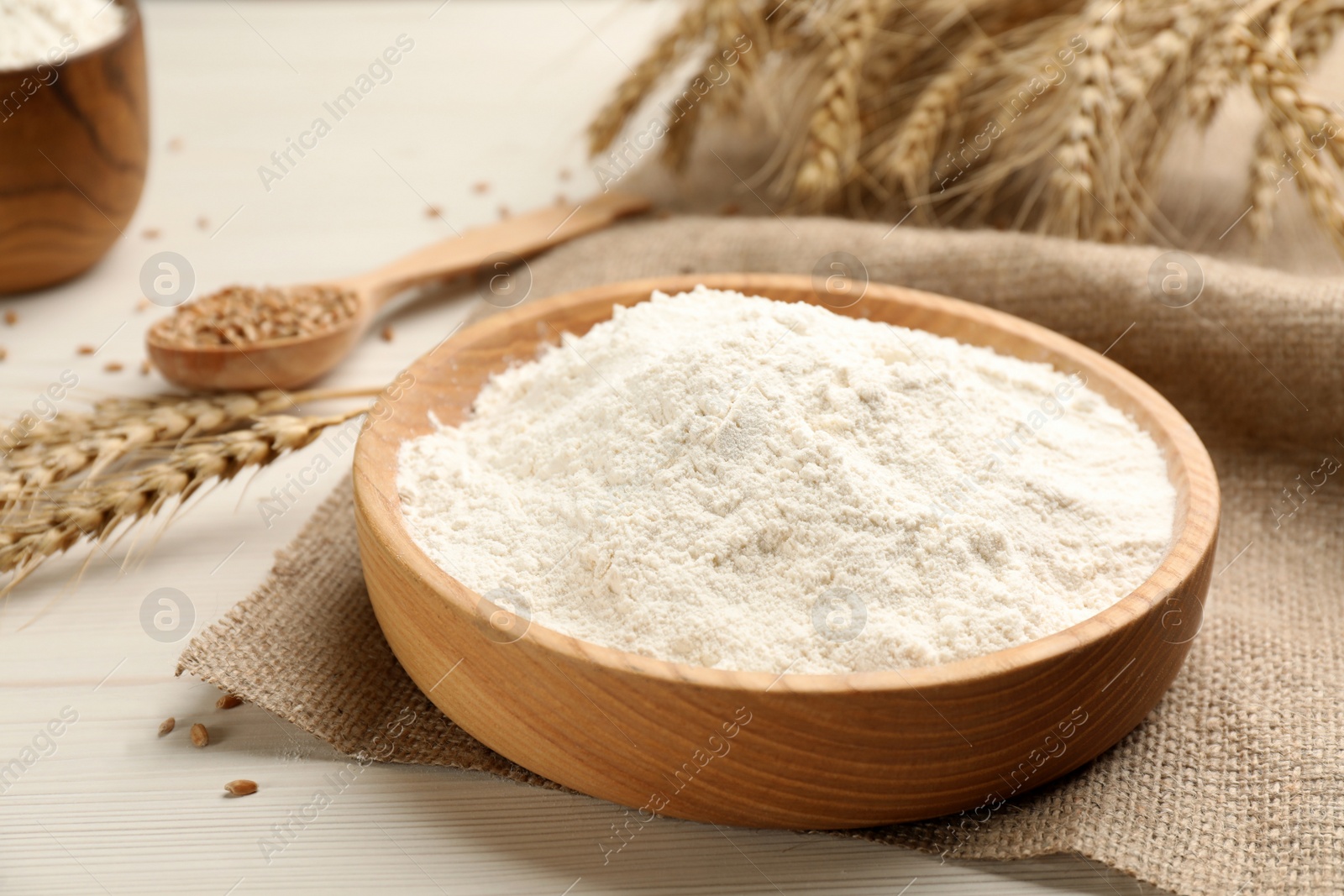 Photo of Plate with wheat flour on white wooden table