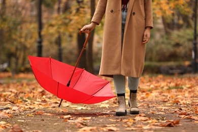 Woman with red umbrella walking in autumn park, closeup