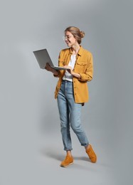 Photo of Full length portrait of young woman with modern laptop on grey background