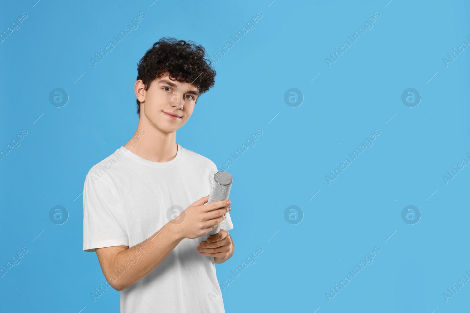 Photo of Teenage boy with party popper on light blue background. Space for text