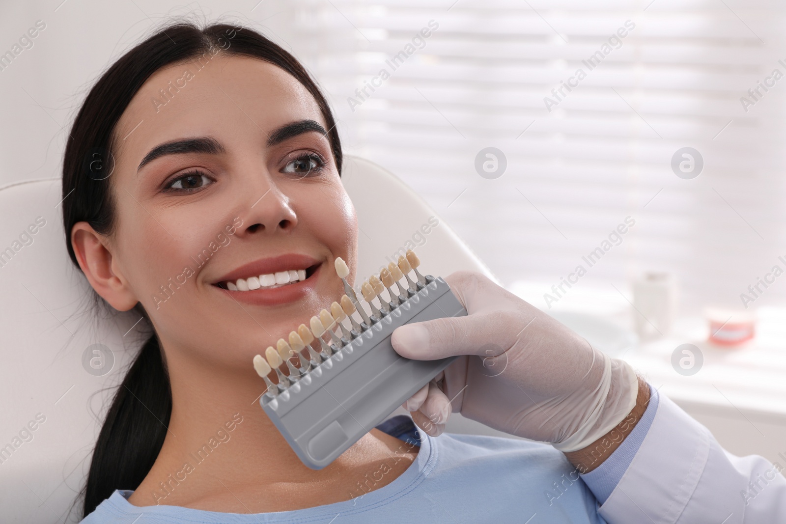 Photo of Dentist checking young woman's teeth color in clinic