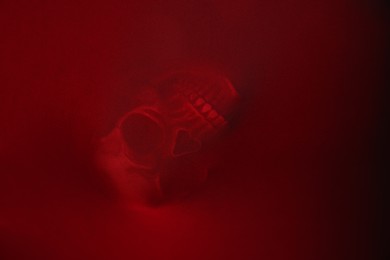 Photo of Silhouette of creepy ghost with skull behind red cloth