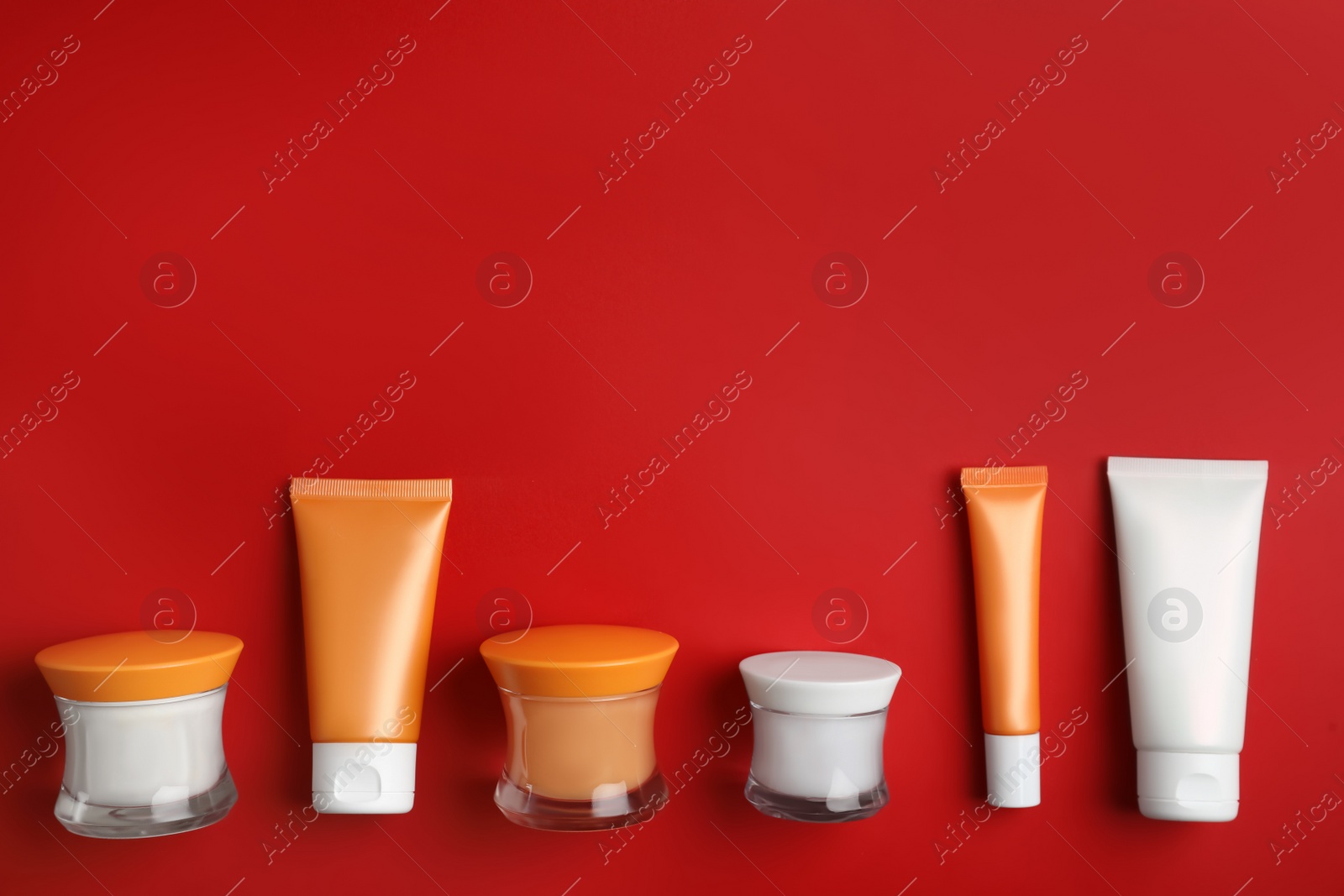 Photo of Set of luxury cosmetic products on red background, flat lay. Space for text