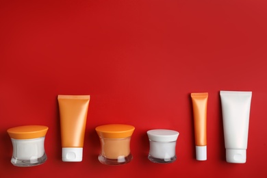 Photo of Set of luxury cosmetic products on red background, flat lay. Space for text