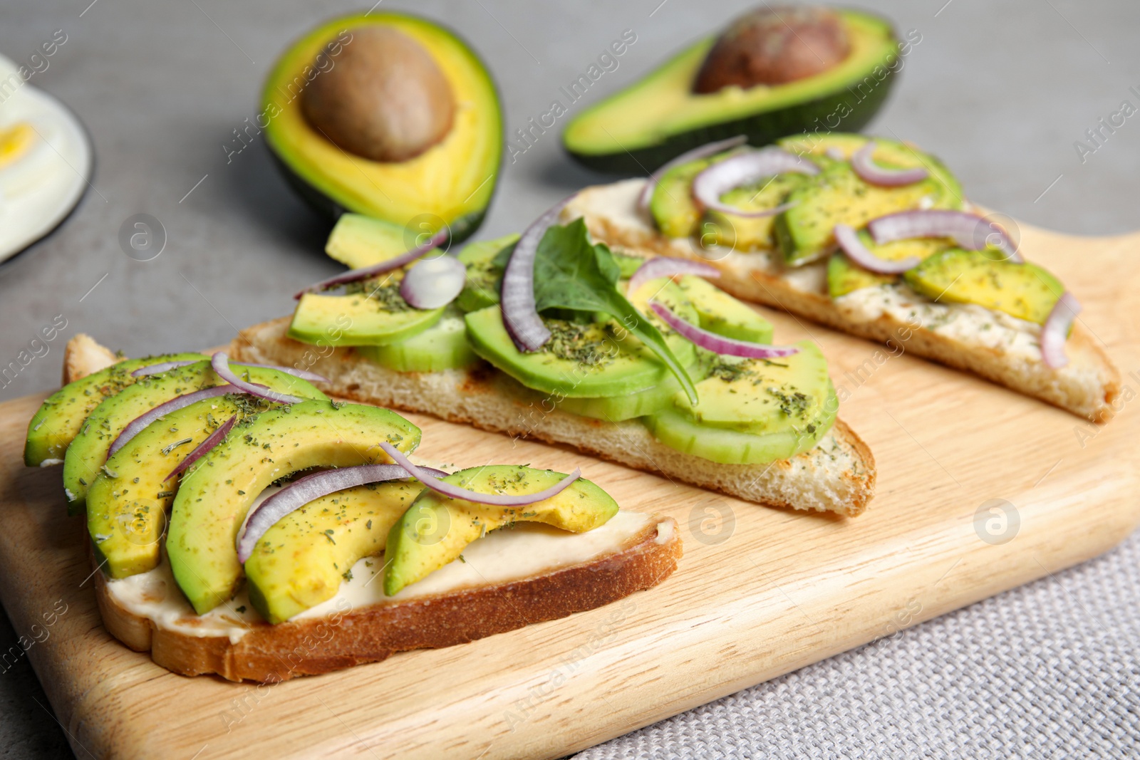 Photo of Tasty avocado toasts served on light grey table, closeup