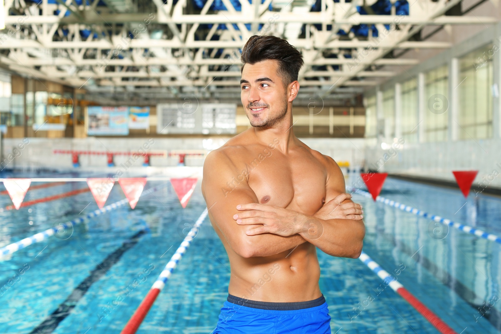 Photo of Young athletic man near swimming pool indoors