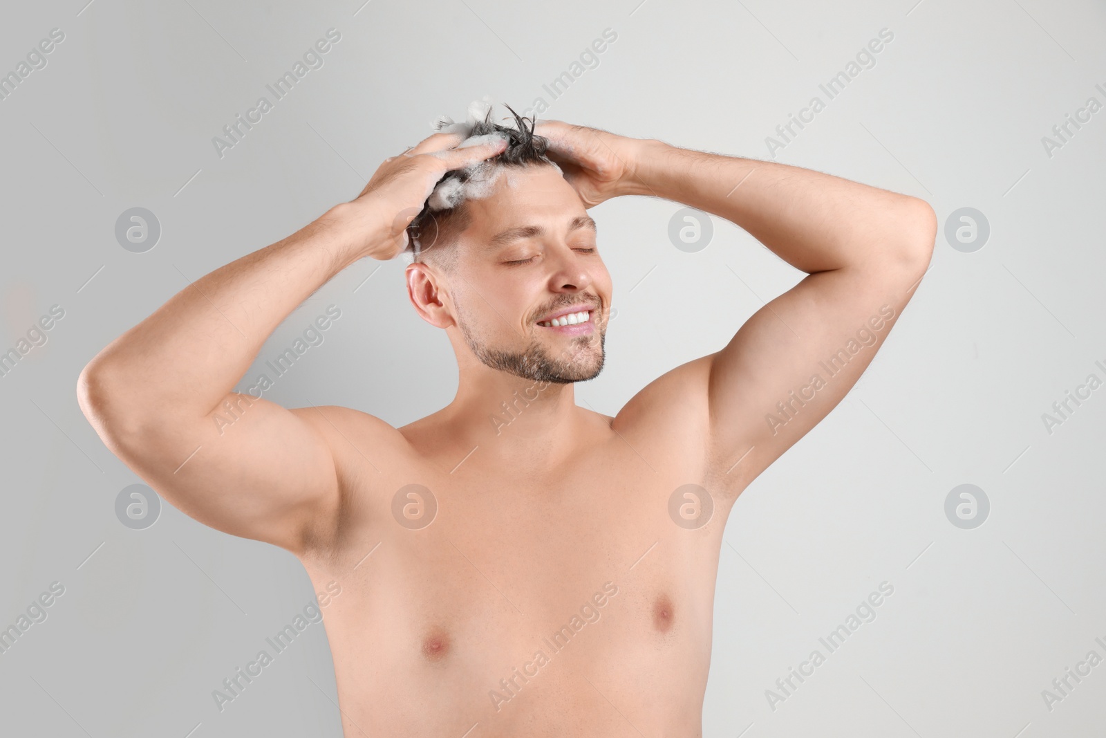 Photo of Handsome man washing hair on white background