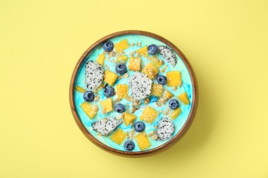 Delicious smoothie bowl with fresh fruits, blueberries and oatmeal on yellow background, top view