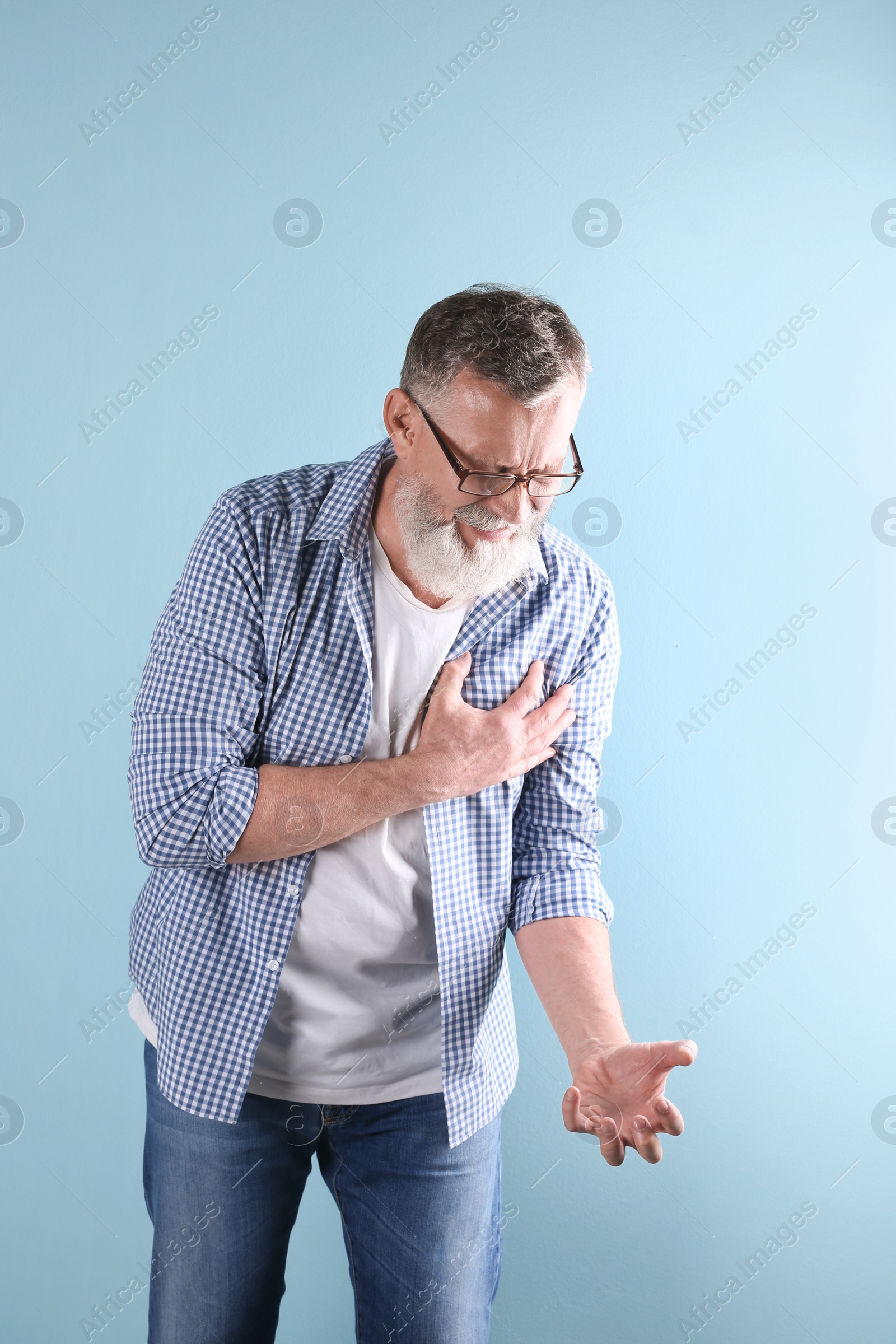 Photo of Mature man having heart attack on color background