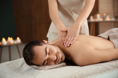 Photo of Handsome man receiving back massage in spa salon