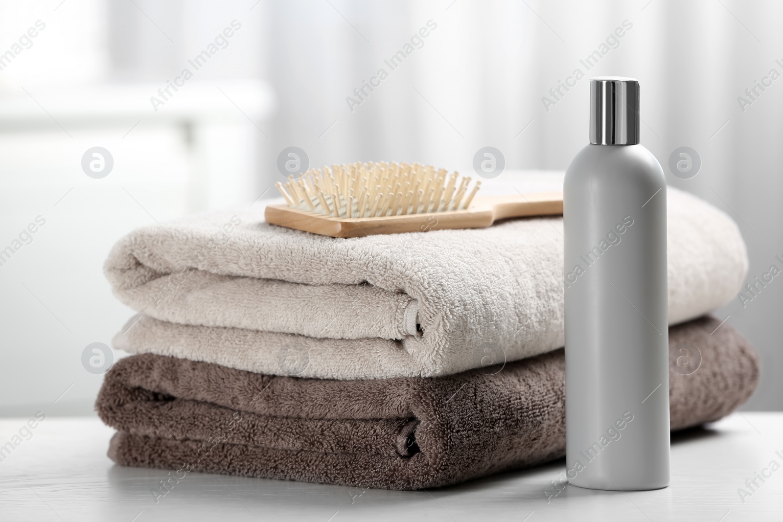 Photo of Towels with hair brush and shampoo on table