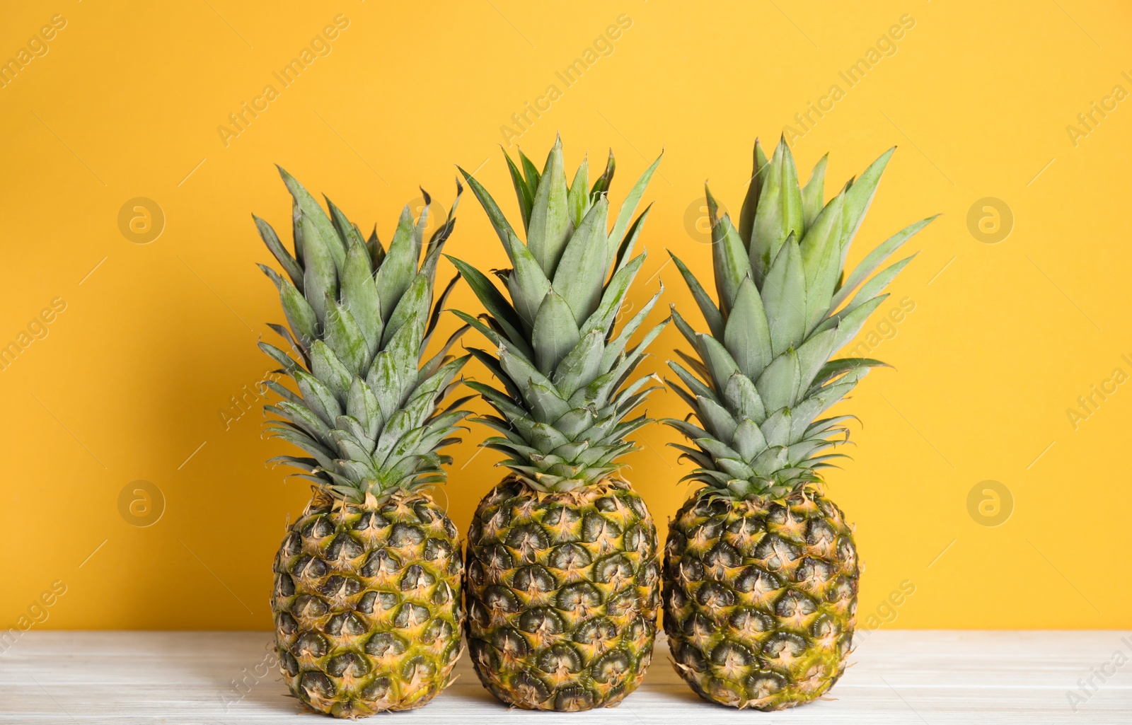 Photo of Fresh ripe juicy pineapples on white wooden table