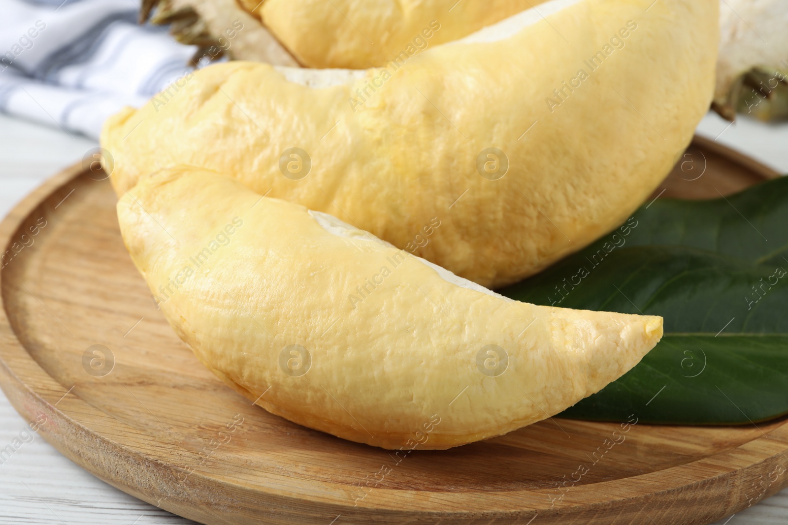 Photo of Pieces of fresh ripe durian on wooden plate, closeup