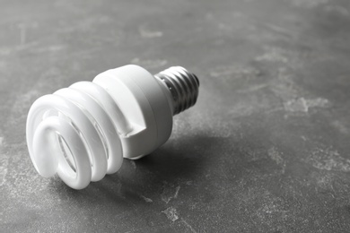 Photo of New fluorescent lamp bulb on grey stone surface. Space for text