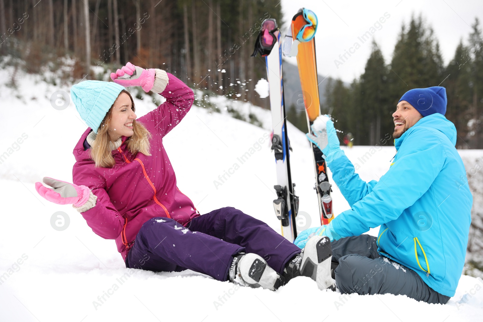 Photo of Couple of skiers playing with snow outdoors. Winter vacation