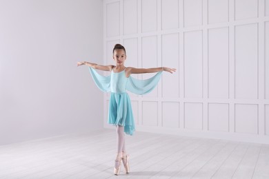 Beautifully dressed little ballerina dancing in studio. Space for text 