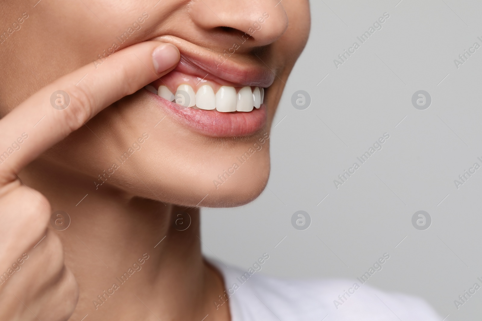 Photo of Woman showing healthy gums on light background, closeup. Space for text