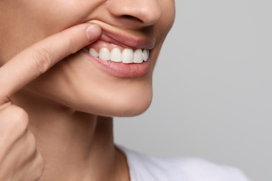 Woman showing healthy gums on light background, closeup. Space for text