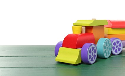 Photo of Colorful wooden train on green table against white background, space for text. Children's toy