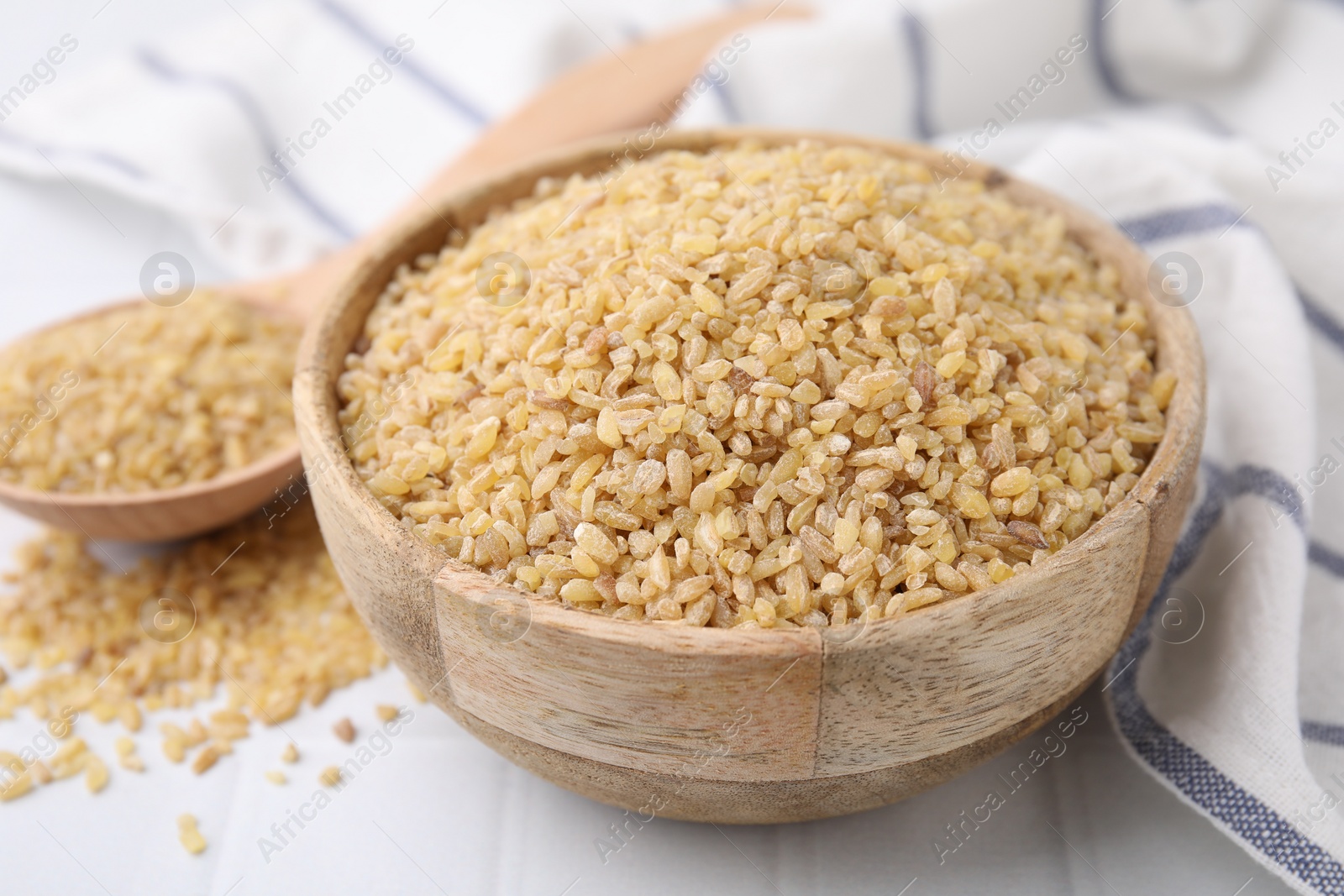 Photo of Raw bulgur in bowl on table, closeup