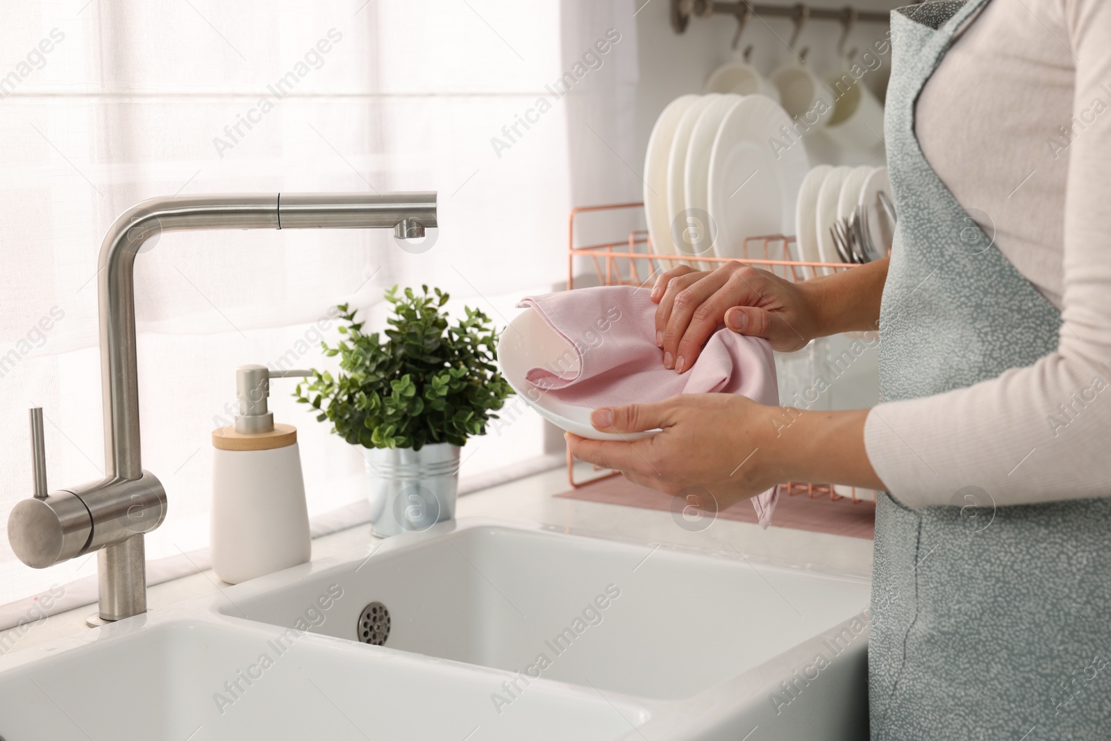 Photo of Woman wiping bowl with towel in kitchen, closeup