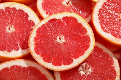 Photo of Many sliced fresh ripe grapefruits as background, closeup