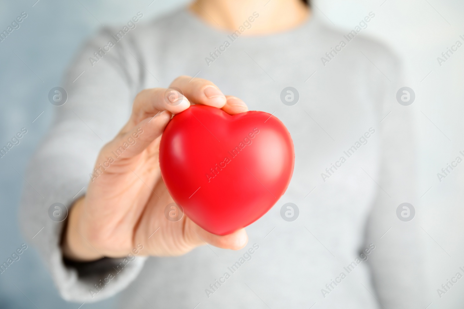 Photo of Woman holding red heart against color background, closeup. Cardiology concept