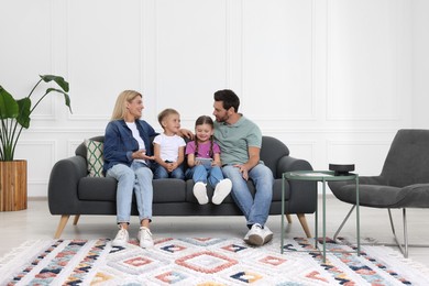 Happy family with smartphone spending time together on sofa at home