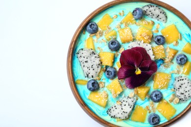 Photo of Delicious smoothie bowl with fresh fruits, blueberries, flower and oatmeal on white background, top view. Space for text