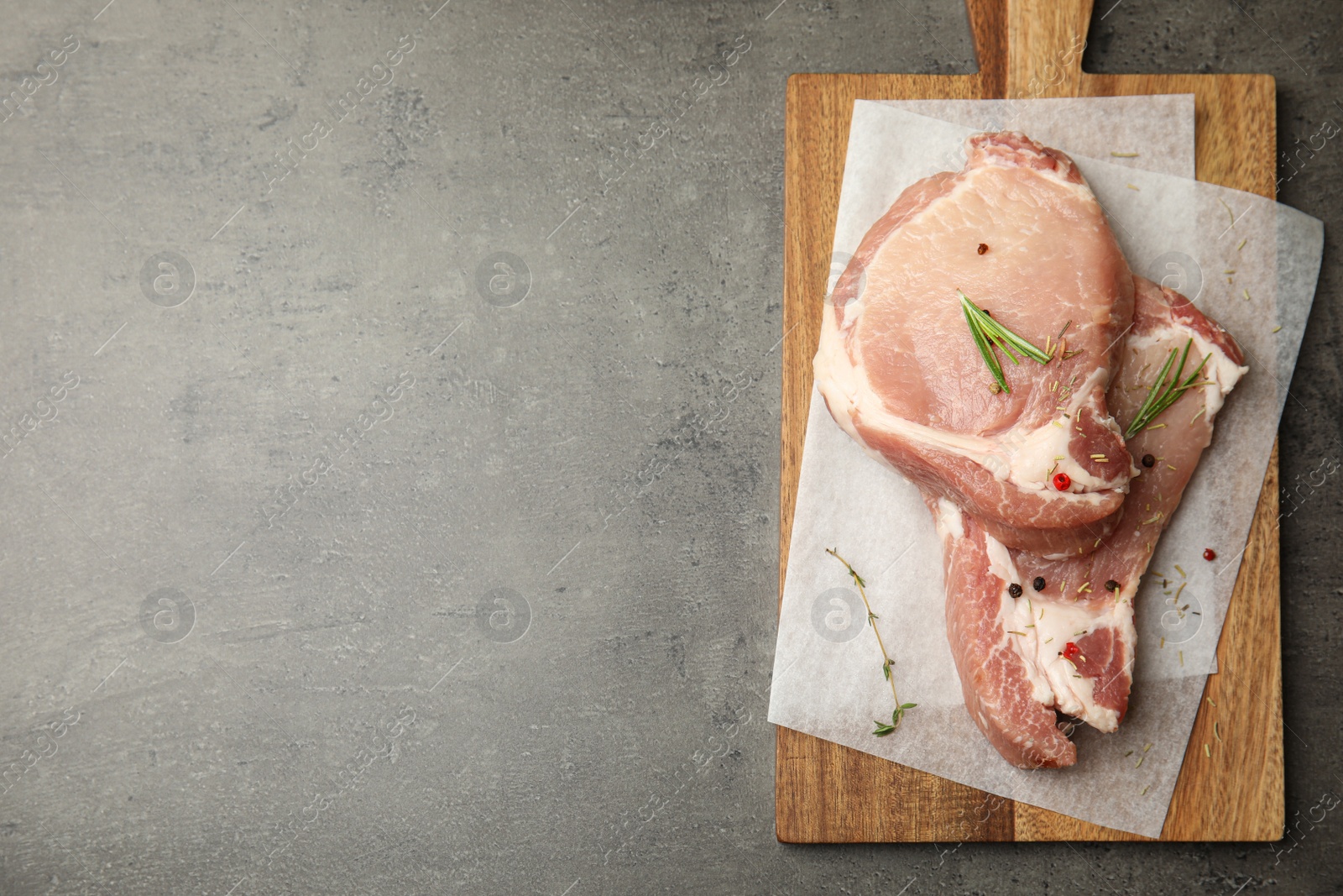 Photo of Fresh raw beef cut with spices on grey table, top view. Space for text