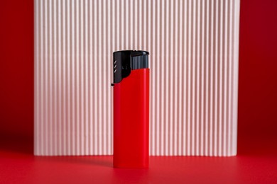 Stylish small pocket lighter and white corrugated fiberboard on red background
