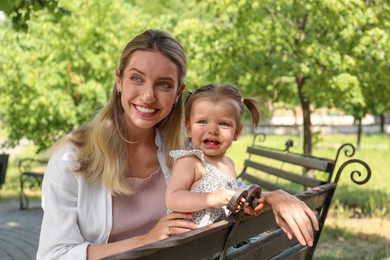 Photo of Happy mother with her daughter sitting on bench in park