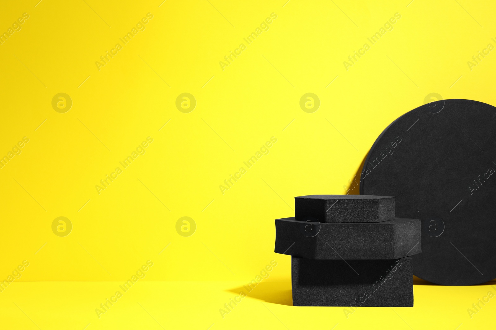 Photo of Many black geometric figures on yellow background, space for text. Stylish presentation for product
