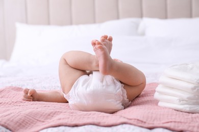 Little baby and stack of diapers on bed, closeup