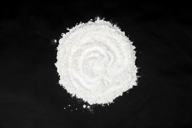 Photo of Pile of flour on black table, top view