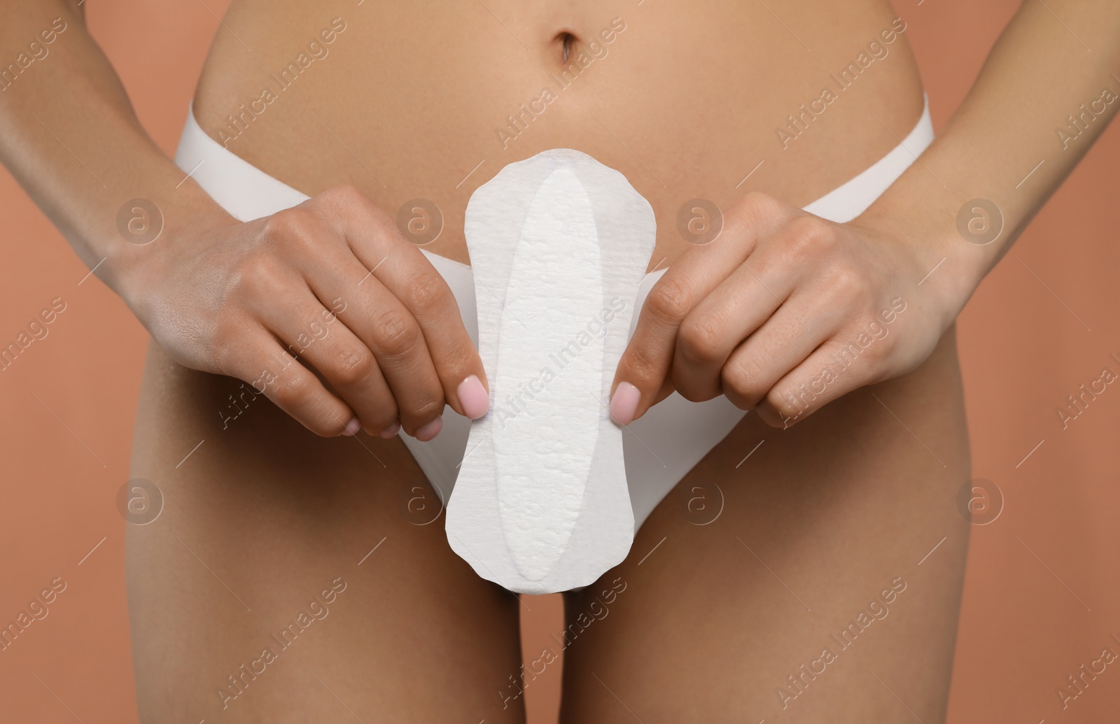 Photo of Woman in white panties with menstrual pad on peach background, closeup