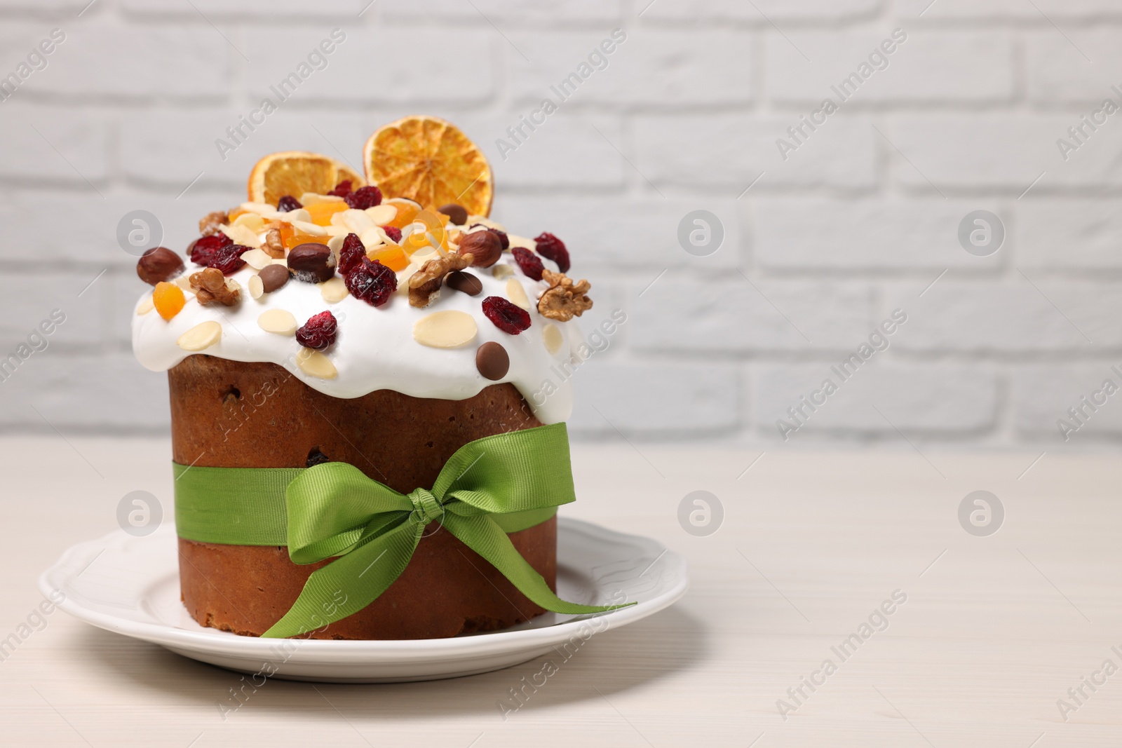 Photo of Tasty Easter cake with dried fruits and nuts on white wooden table. Space for text