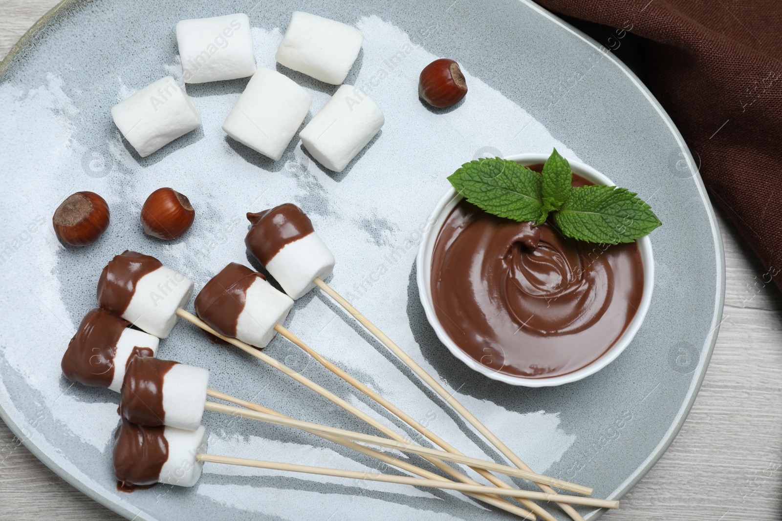 Photo of Tasty marshmallows dipped into chocolate on white wooden table, top view